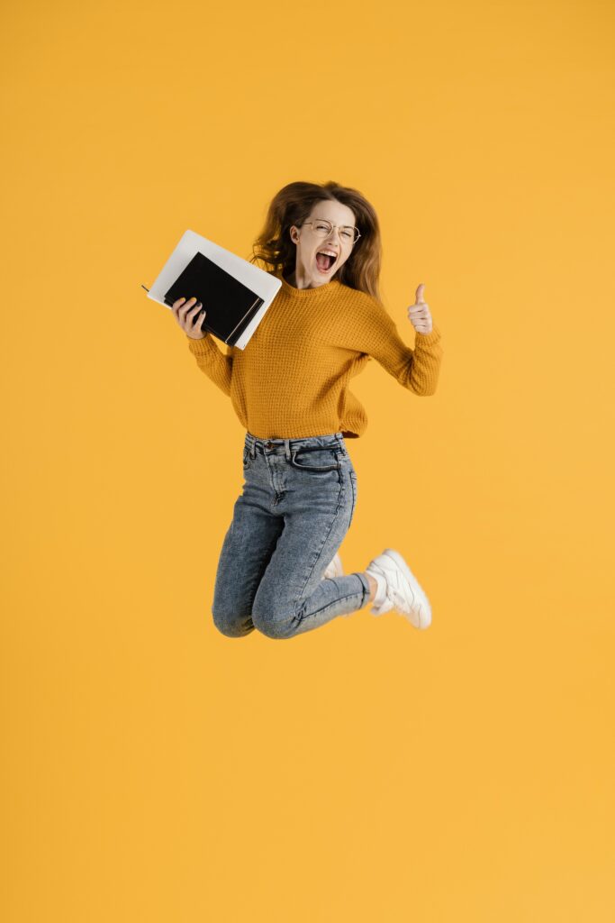 portrait-young-female-jumping-holding-books